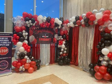 Colorful balloon arch and backdrop for a graduation celebration.