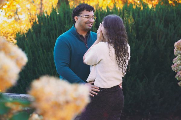 Couple sharing a joyful moment outdoors surrounded by autumn foliage.