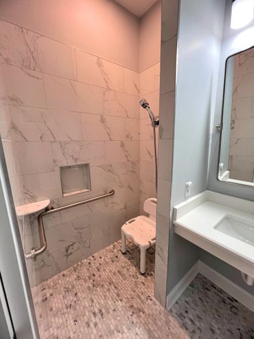 Modern bathroom with marble tiles and a shower seat for accessibility.