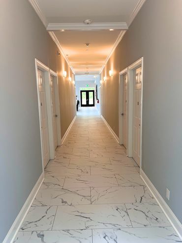 A bright hallway with marble flooring and white doors on each side.