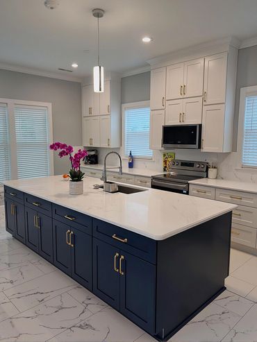 Modern kitchen with navy blue island and white cabinetry accented by gold handles.