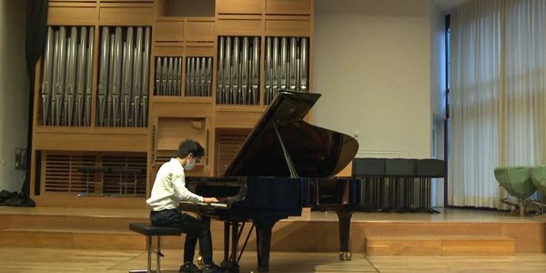 Kind spielt Klavier auf Bühne.