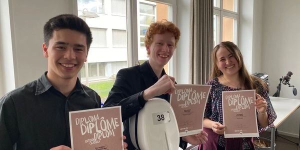 Drei glückliche Menschen zeigen stolz Diplome.