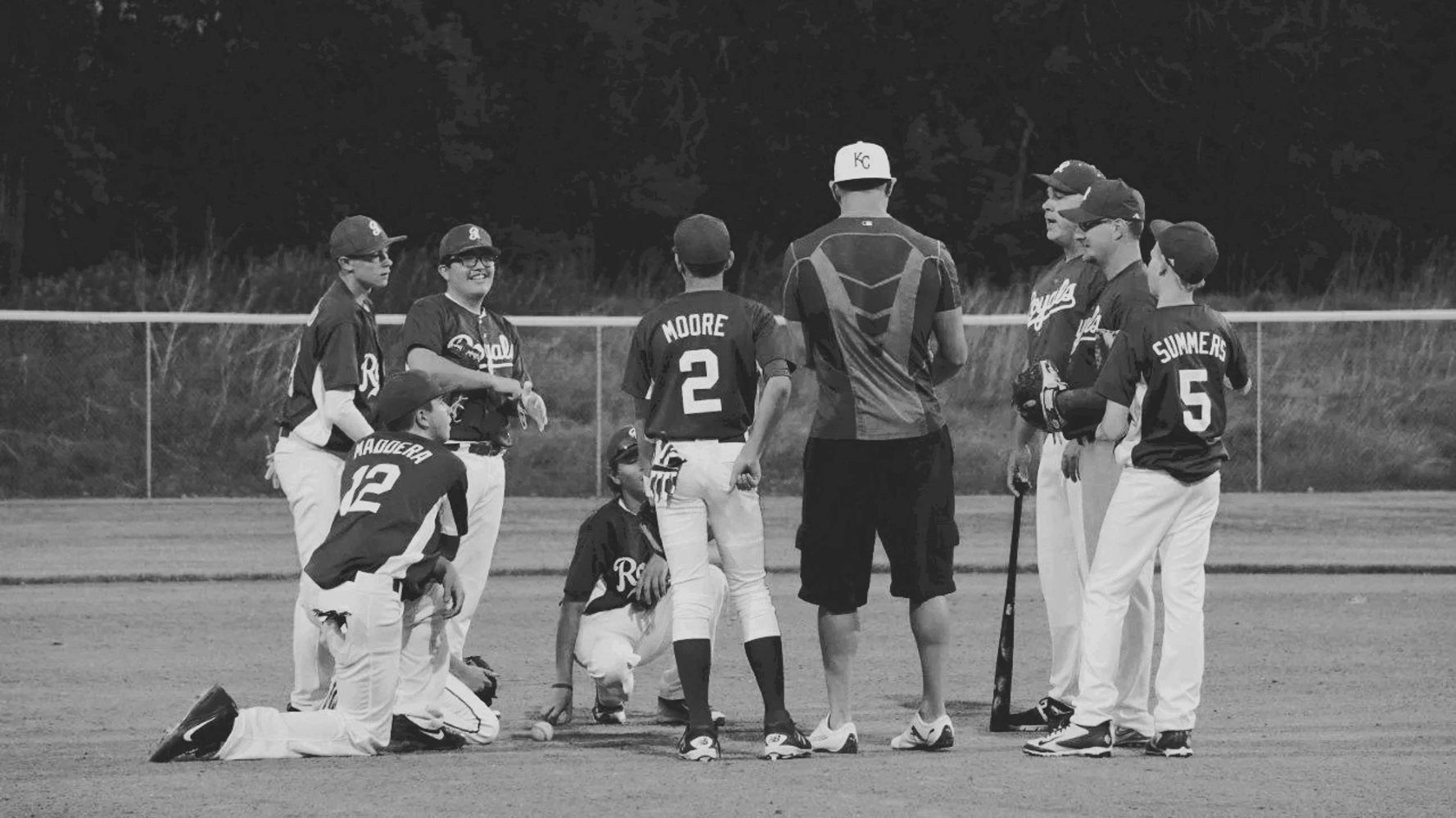 Youth baseball team and coach having a discussion on the field.