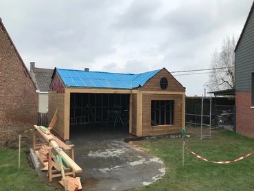 Tuinhuis in opbouw met zicht op houten constructie en dakbedekking in voorbereiding.