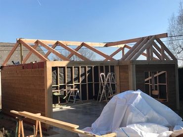 Houten tuinhuis in constructiefase met zicht op gebinte en open zijmuren, klaar voor dakafwerking.
