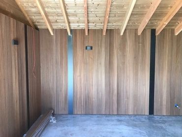 Binnenafwerking van het tuinhuis, met geribde thermo ayous wandbekleding en houten dakstructuur.