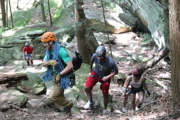 rappelling group hiking to their next amazing location in the hocking hills climbing and rappelling