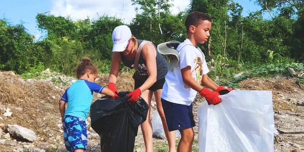 a mom and kids gathering trash in plastic bags during a coastal clean up event with gloves and bags