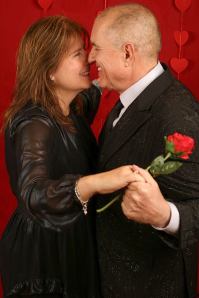 Couple romantically dancing and smiling with a rose in hand.