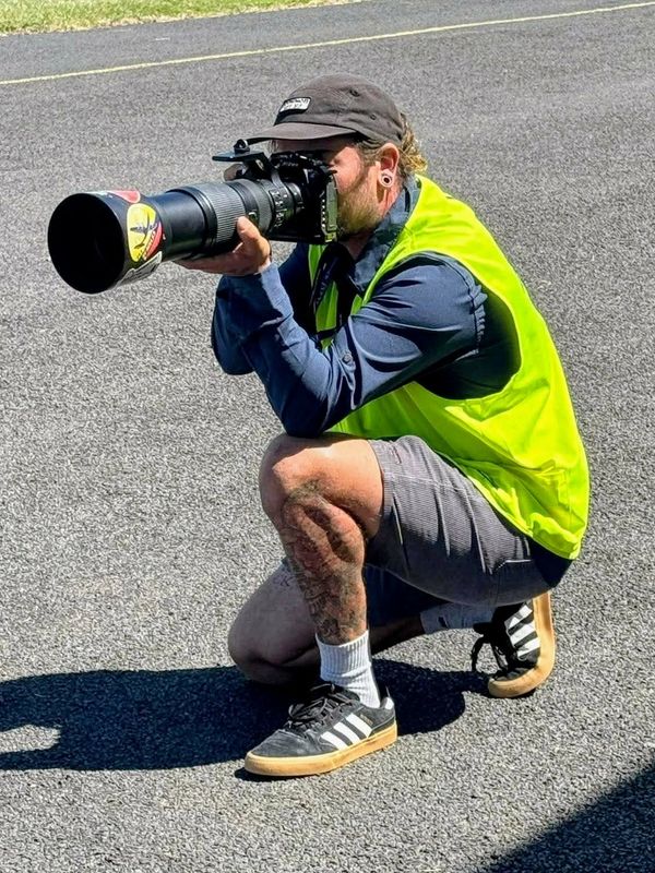 Photographer in a neon vest crouching and taking a photo.