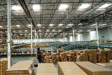 A vast warehouse filled with stacked cardboard boxes and shelves