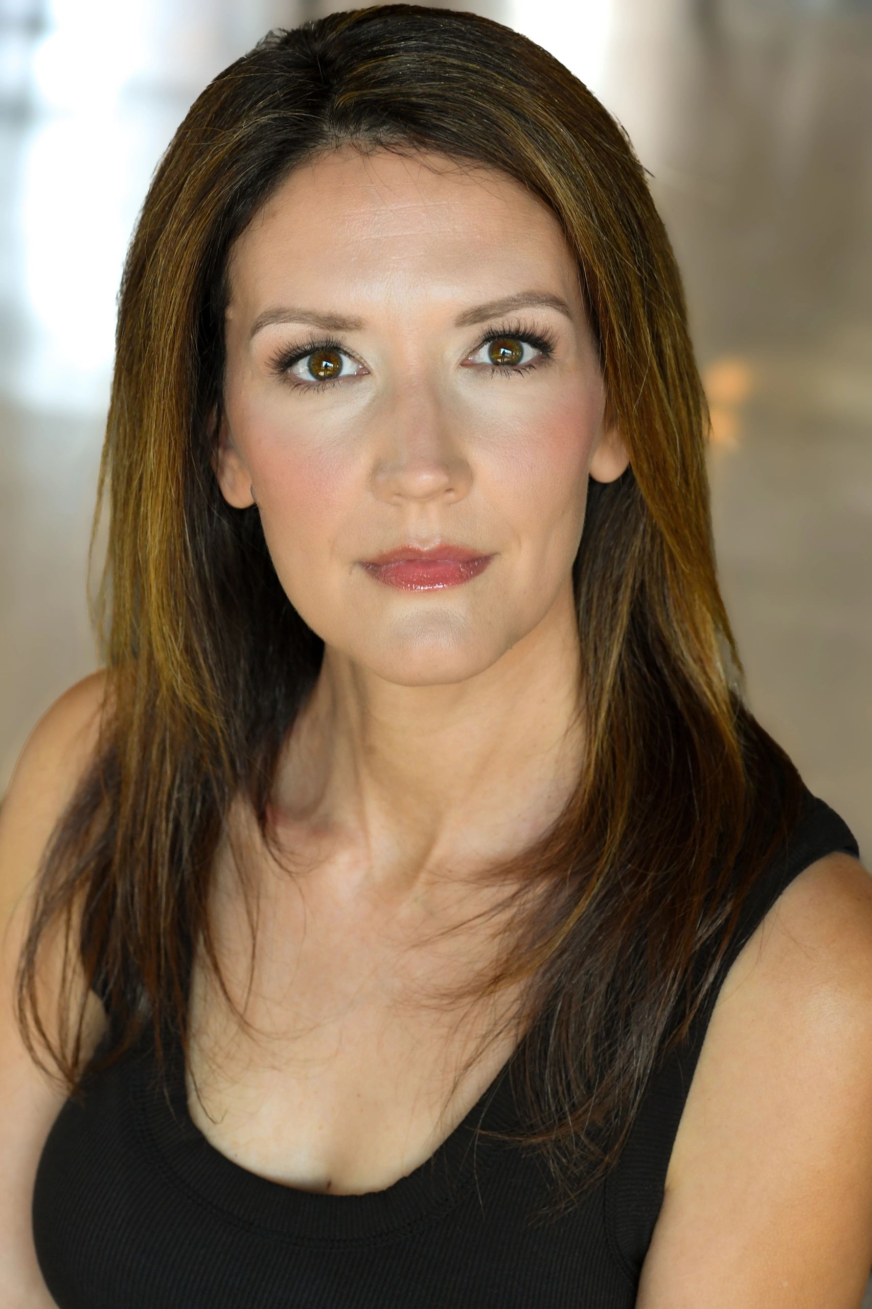 Close-up portrait of a woman with brown hair and hazel eyes, wearing a black top.