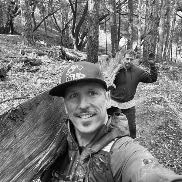Two men carrying a log in a forest.