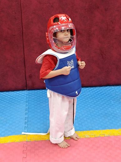 Korumalı kıyafet giymiş çocuk dövüş sporları stüdyosunda.
