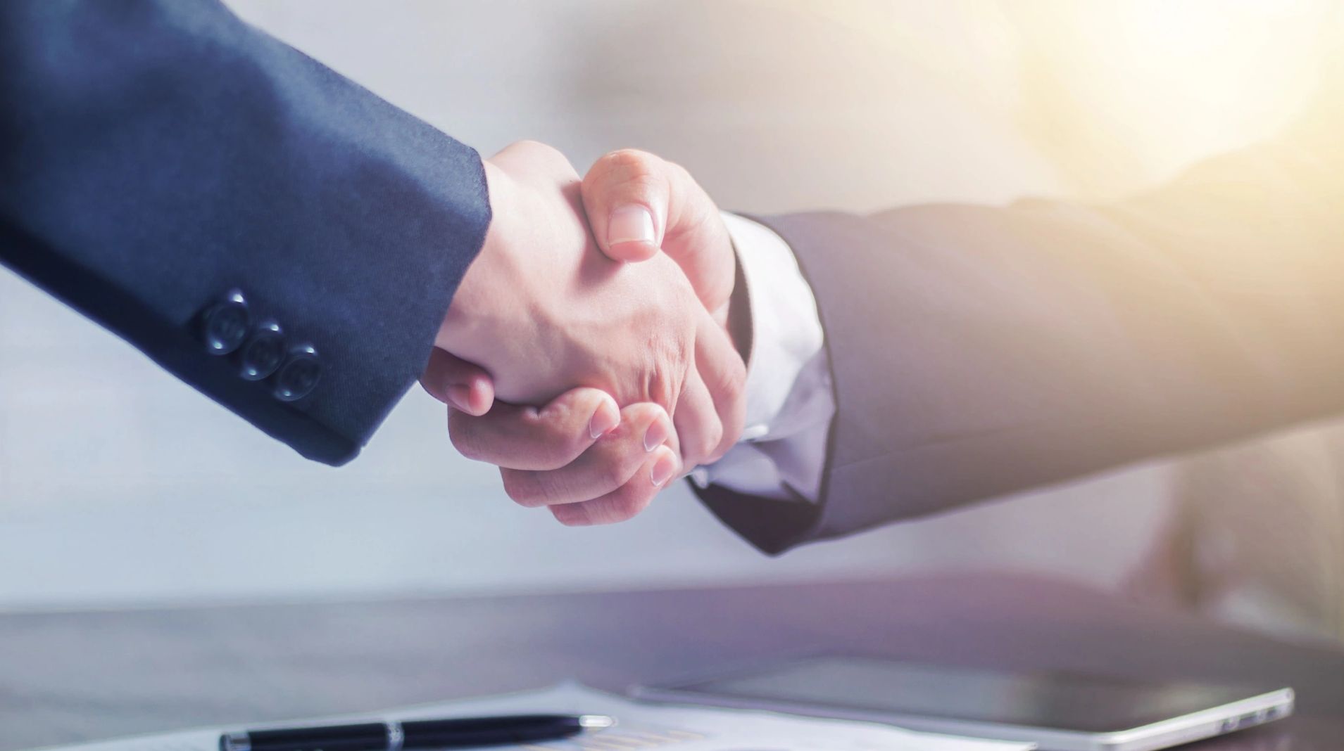 Two people shaking hands in a business setting.