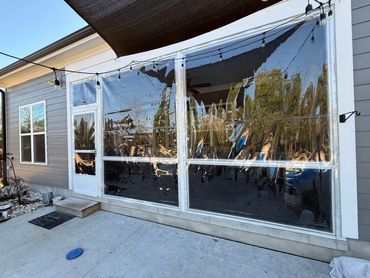 Back patio with clear plastic windbreakers and string lights.