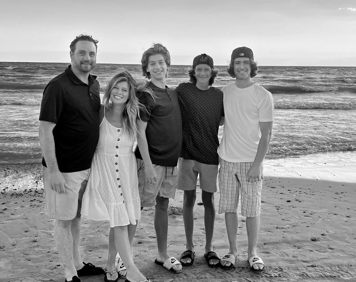Family standing together on the beach at sunset.