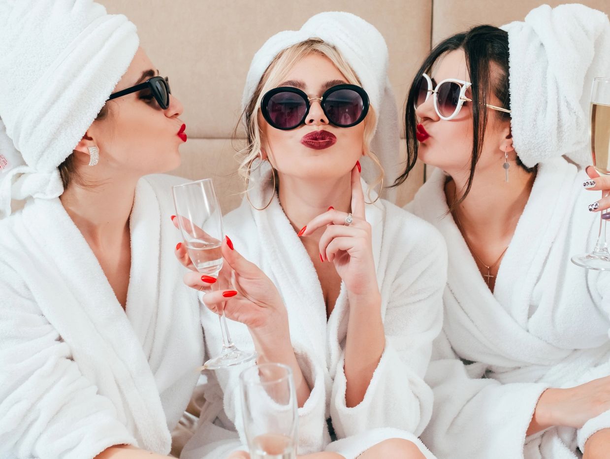 Three women in spa robes with sunglasses and champagne classes