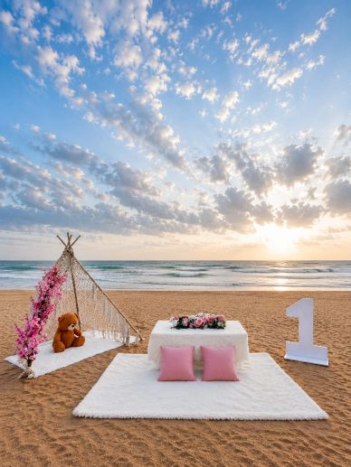 A beach setup with a tent, teddy bear, and number one decoration.