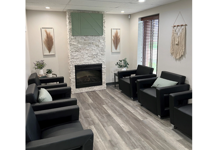 Peaceful waiting room with black chairs and a fireplace.