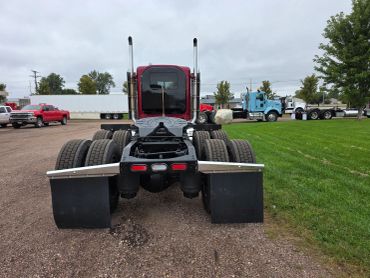 Rear view of a red semi-truck cab without trailer.