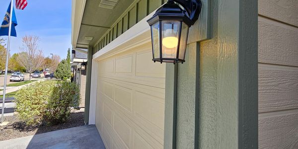 Exterior view of a house garage with an outdoor lantern light on.