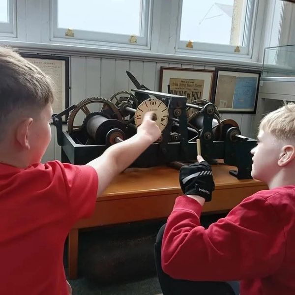 children from seaton primary school looking at an old clock movement at seaton museum