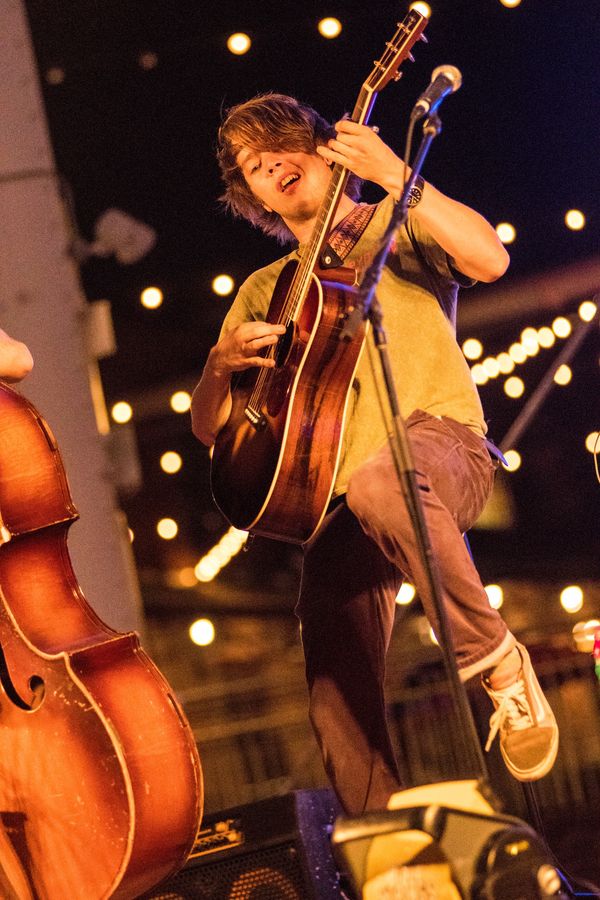 Guitarist under string lights.