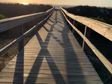 Wooden boardwalk leading to the beach at sunset.