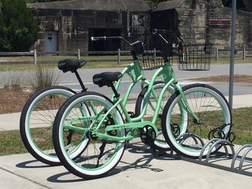 Two mint green bicycles parked in a bike rack on a sunny day.