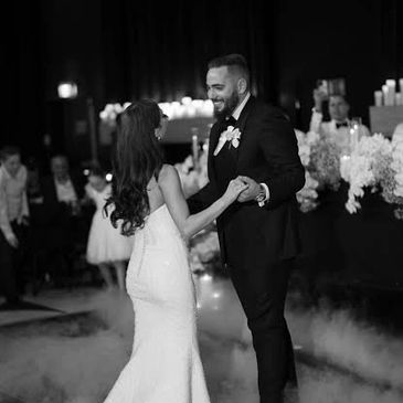 Bride and groom dancing at their wedding reception surrounded by guests.