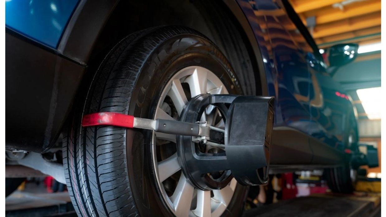 Close-up of a car tire with a wheel alignment tool attached in a workshop.