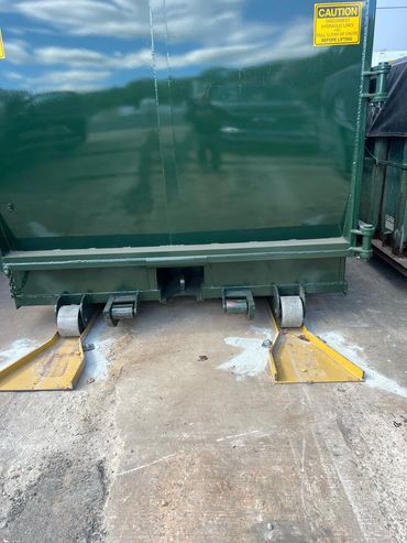 Rear of self-contained compactor seated on yellow guide rails, Elite Containers build-out