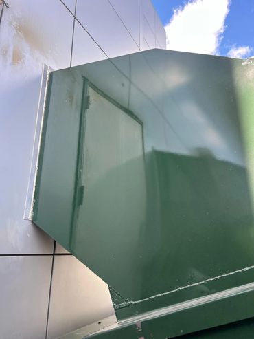 Green exterior trash chute enclosure against building wall, Elite Containers build-out