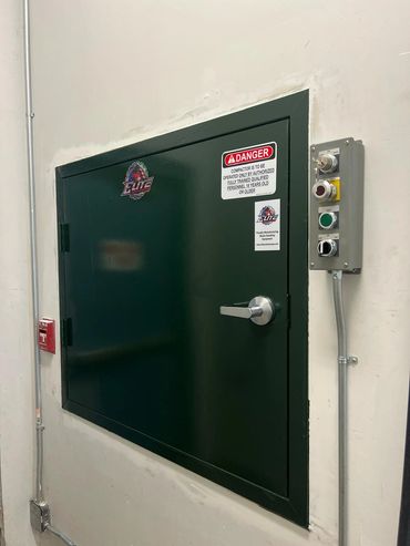 Interior chute door with Elite crest, controls and safety signage, Elite Containers build-out