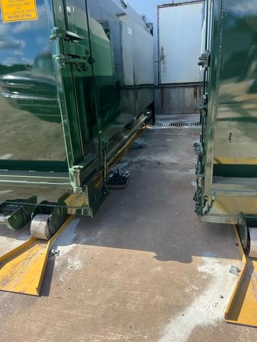 Two self-contained compactors on yellow guide rails, Elite Containers build-out