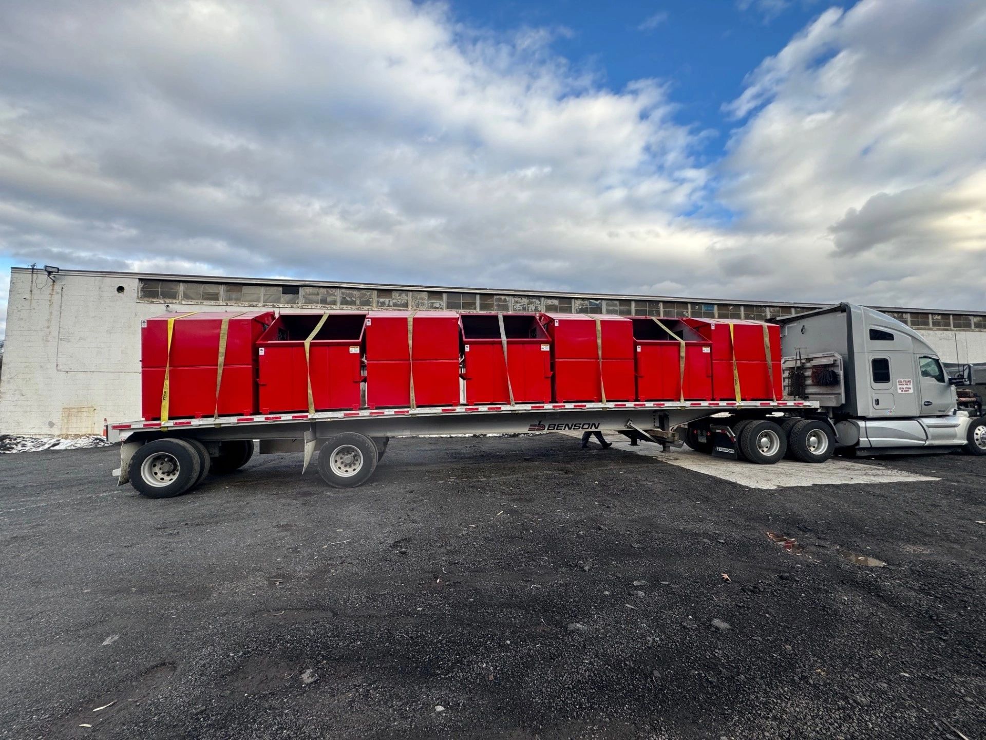 Red steel containers strapped to a flatbed trailer at Elite Containers