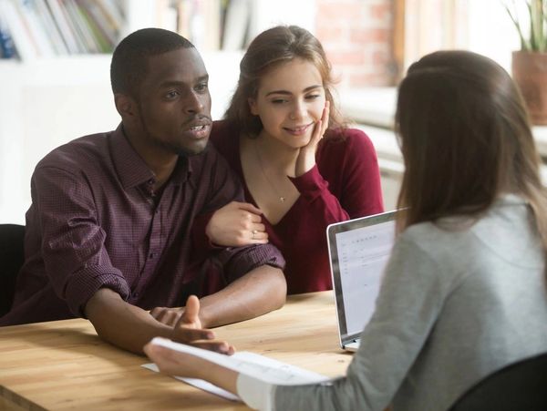 Multiethnic couple describing their dream house to real estate agent. African american husband telli