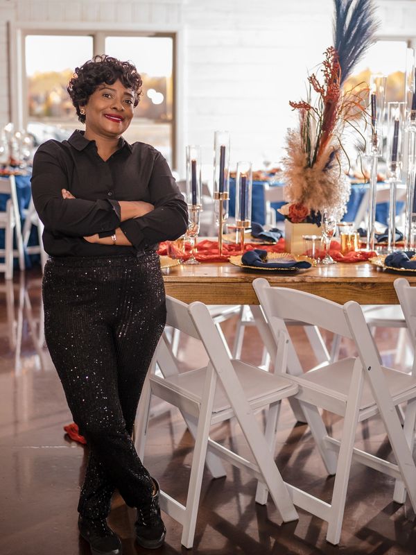 Woman standing confidently in a decorated dining hall.