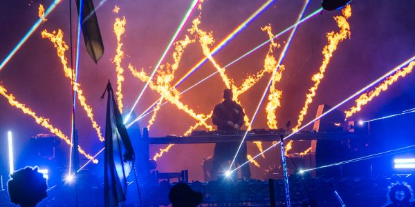 DJ performing on stage with fire and laser lights.