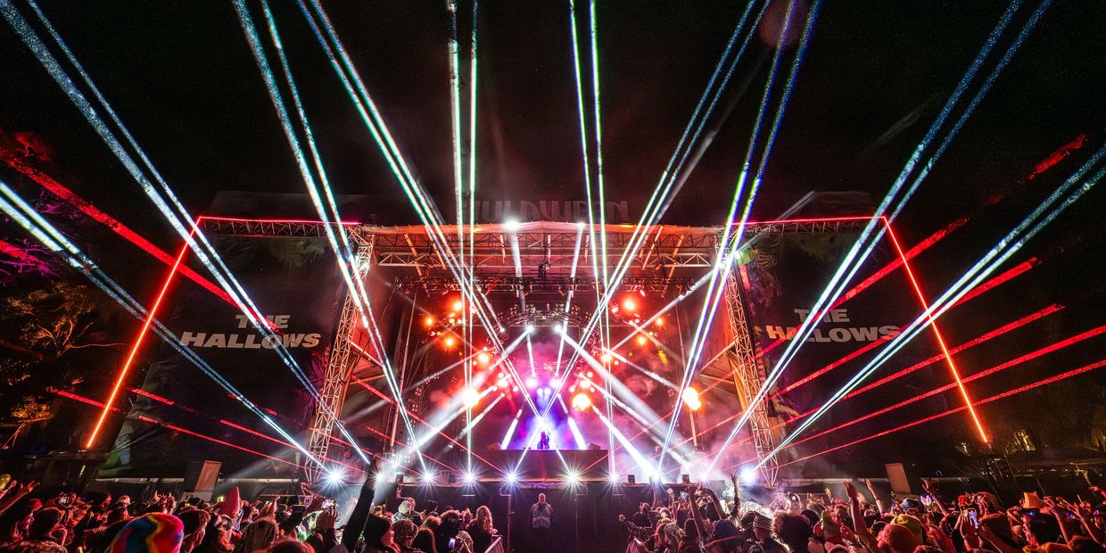 Concert stage with colorful laser lights and crowd at night.
