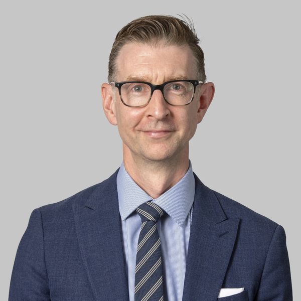 Professional man in glasses wearing a blue suit and striped tie.