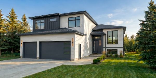 Modern two-story house with a three-car garage and manicured lawn.