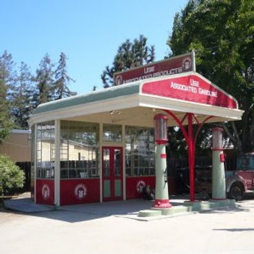 Historic red and white gas station with vintage pumps and canopy.