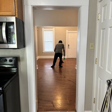 Person cleaning a hardwood floor inside a house.