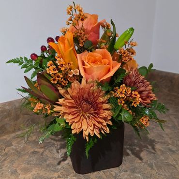 Fall flower arrangement in a cube vase with Orange Lilies and Roses