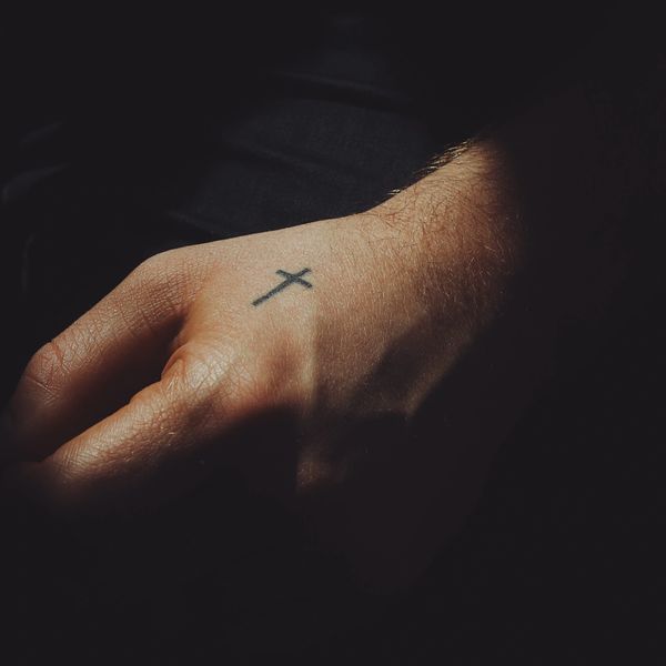 An outstretched hand with cross tatoo.