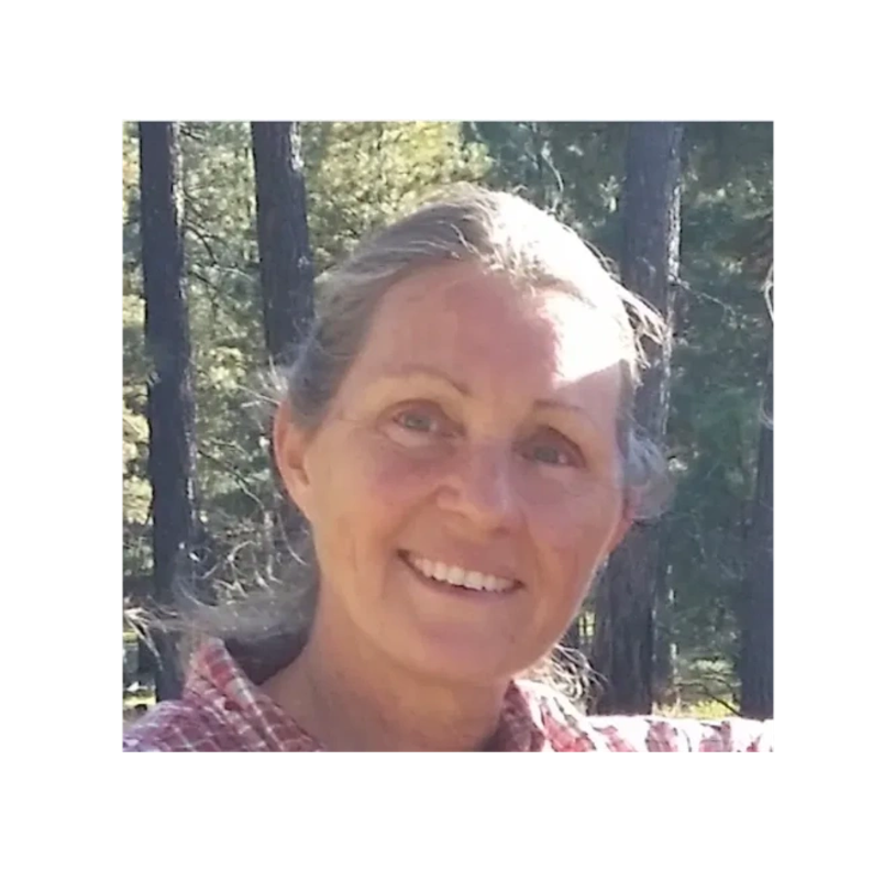 Woman smiling outdoors with trees in background