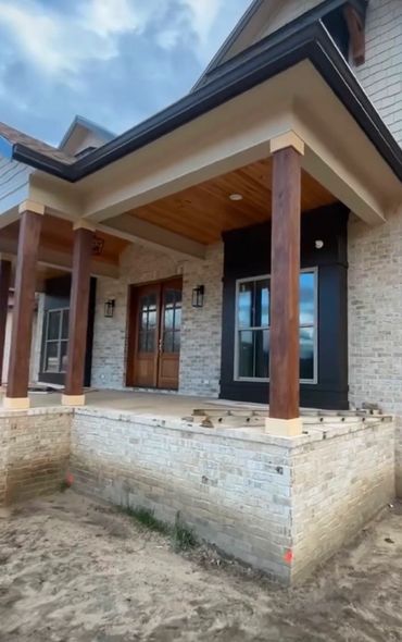 A modern porch with wooden pillars and brick exterior walls.